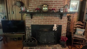A living room with a brick fireplace, a television, and a wooden chair. - Superb 5-bedroom house walking distance to charming downtown Saluda (Saluda)