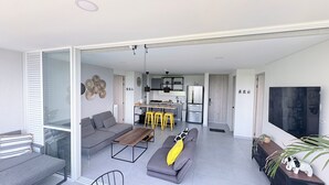 A modern apartment with a grey sofa, a wooden coffee table, a kitchen with a fridge, and a dining area with yellow stools. - 2-bedroom apartment in tranquil Santafe de Antioquia with AC (Santafe de antioquia)