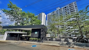 Un edificio moderno con entrada protegida por un portón, un cartel que dice 'CITADELA DI SOLE' y una zona de estacionamiento con motocicletas.
