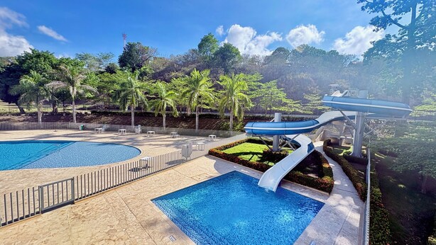 A pool area with two swimming pools, a water slide, and surrounding greenery. - 2-bedroom apartment in tranquil Santafe de Antioquia with AC (Santafe de antioquia)