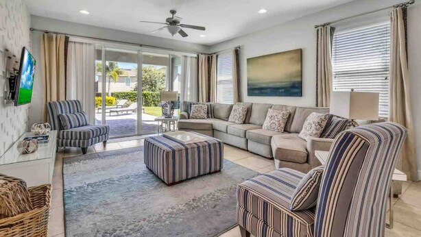 Ein modernes Wohnzimmer mit Sofa, Hocker, Sessel und einem Flachbildfernseher.