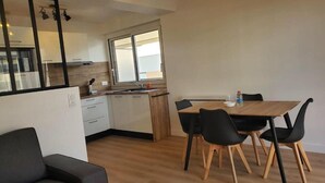 A modern kitchen with a dining area, a sofa, and a window. - L'Appartement Soleil - Clermont Centre (Clermont-Ferrand)