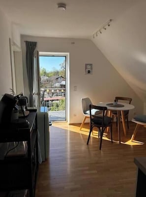 Ein modernes Wohnzimmer mit Essbereich, einem Klavier und einem großen Fenster.