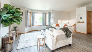 Een slaapkamer met een bed, nachtkastje, lamp, grote plant en uitzicht.