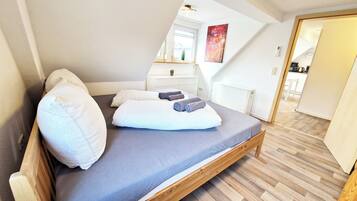 A bedroom with a wooden bed, a gray mattress, and white pillows.