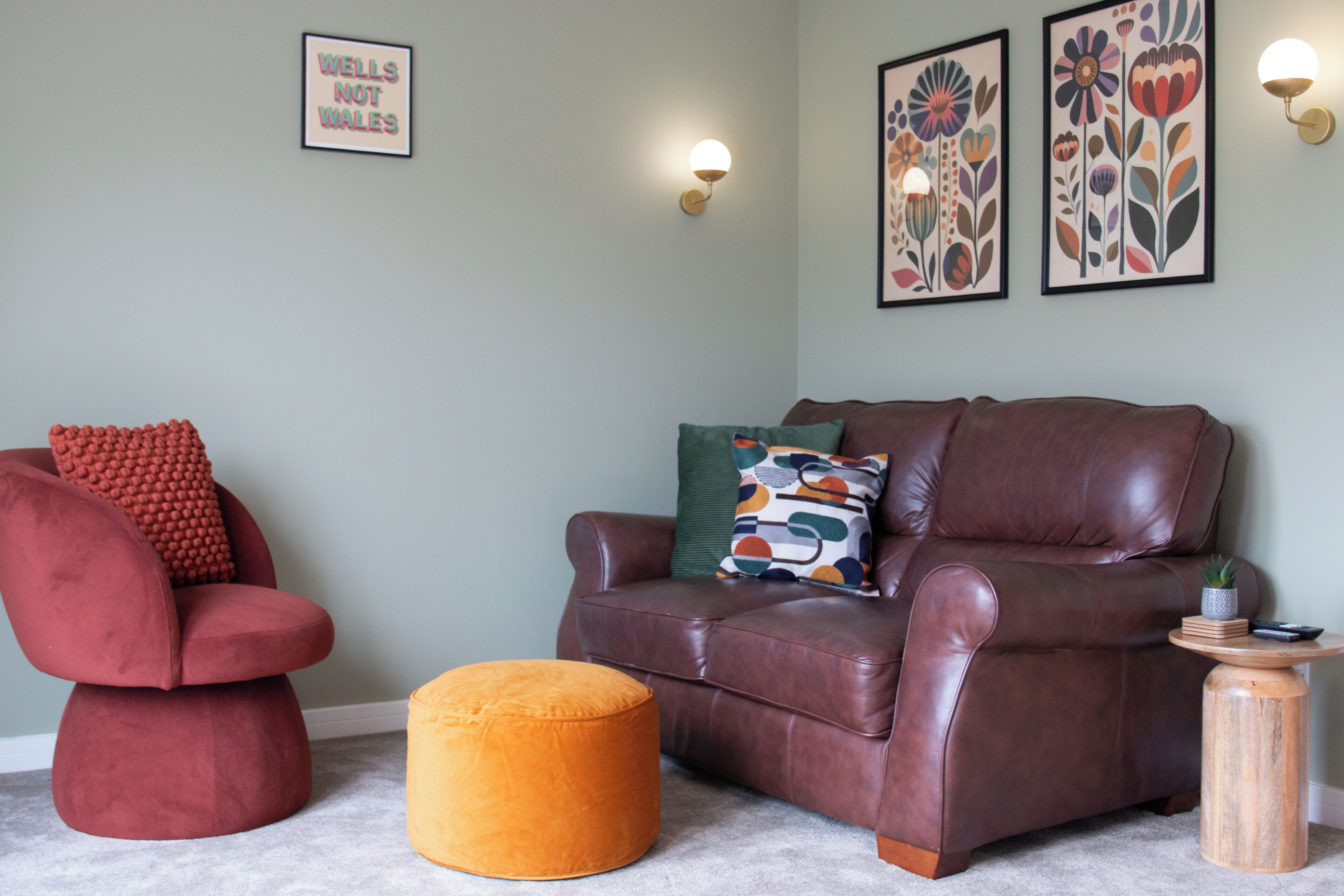 A living room with a brown leather sofa, a red armchair, and an orange ottoman.
