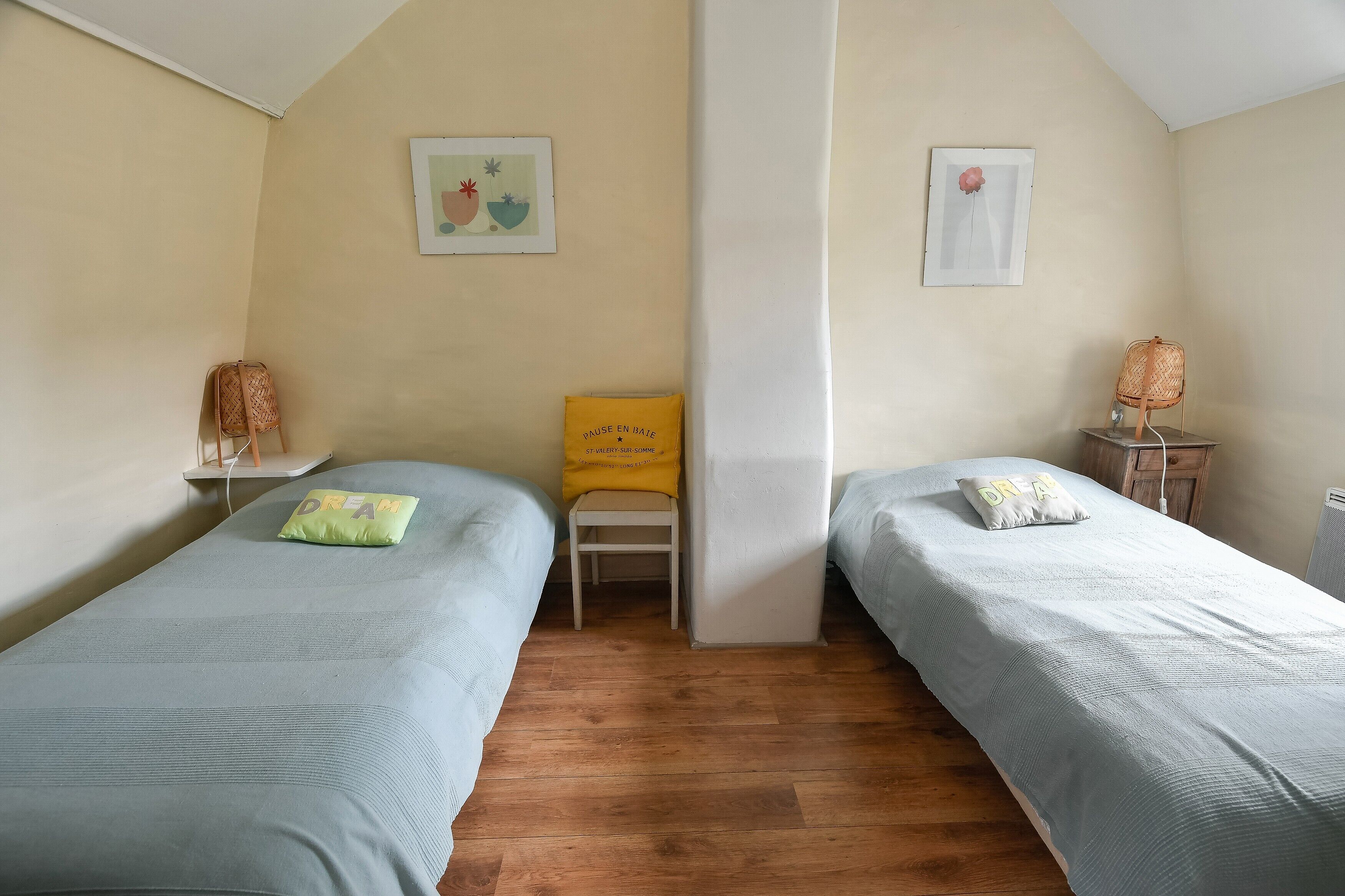 Een kamer met twee bedden, een stoel en een klein tafeltje.