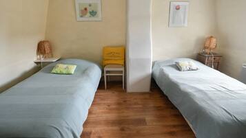 Een kamer met twee bedden, een stoel en een klein tafeltje.