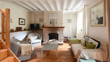 A living room with a fireplace, wooden flooring, a sofa, a coffee table, and a television.