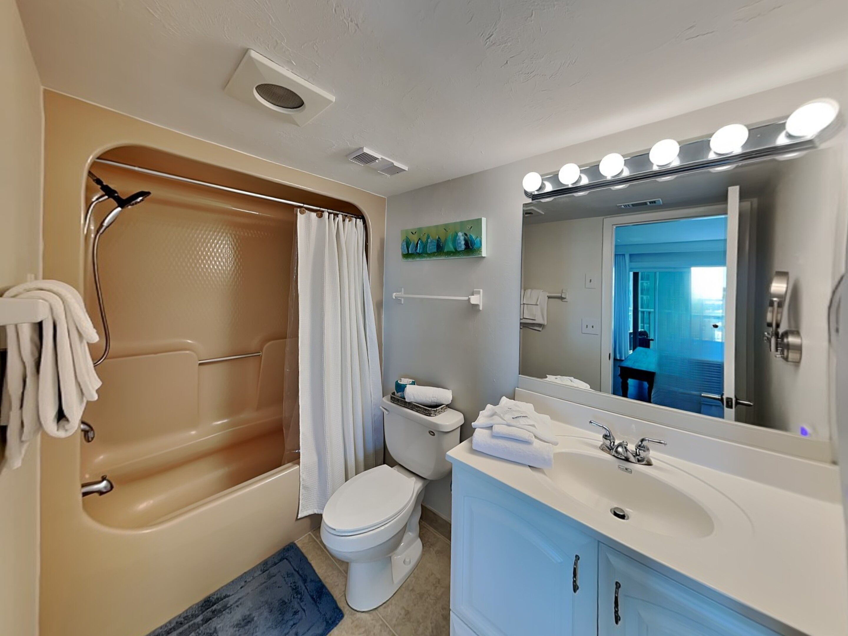 Une salle de bain équipée d’une baignoire, de toilettes, d’un lavabo et d’un miroir avec éclairage.
