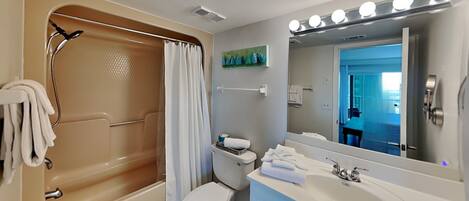 Een badkamer met een bad, toilet, wastafel en spiegel met verlichting.