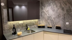 A modern kitchen with a marble backsplash, a built-in oven, and a large mirror above the countertop.