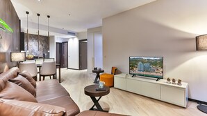 A modern living room with a sofa, dining area, TV, and a view of buildings.