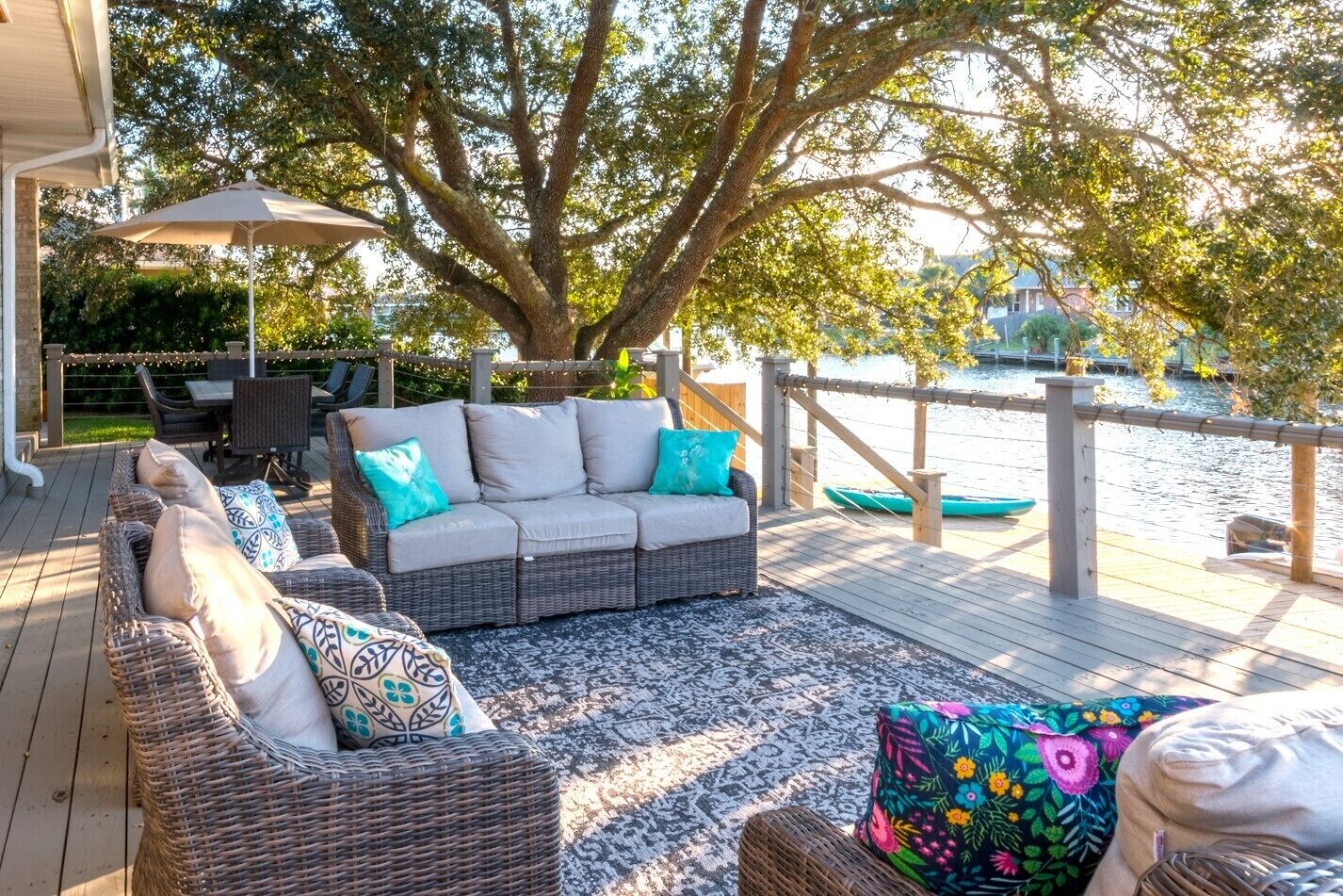 Eine Terrasse mit Korbmöbeln, einem Tisch und Stühlen mit Blick auf ein Gewässer.