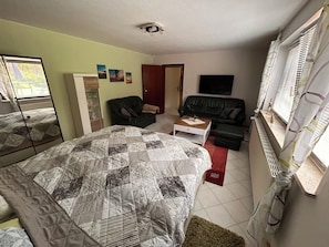 A bedroom with a bed, a sofa, a coffee table, and a TV.