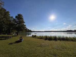 A lakeside setting with a picnic table, a small boat, and a grassy area.