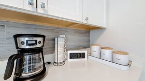 A kitchen with a coffee maker, a coffee station, and containers labeled coffee, tea, and sugar. - Serene 2-bedroom house minutes to Beach Restaurants (Pompano Beach)