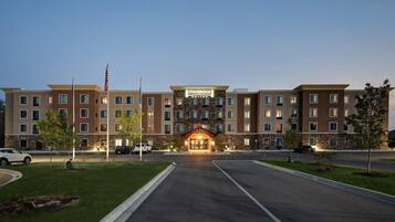 A multi-story hotel with a stone facade, a central entrance, and a parking lot.