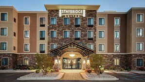 Um hotel Staybridge Suites com fachada de pedra, várias janelas e uma entrada bem iluminada.