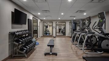 A gym with treadmills, dumbbells, and a bench.