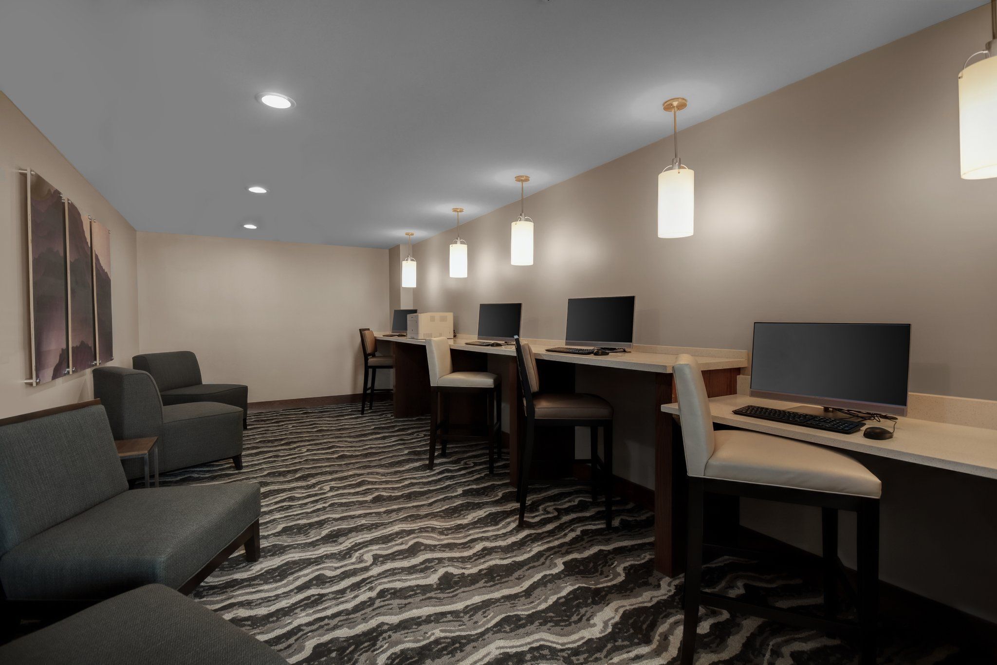 Une chambre d’hôtel équipée d’un bureau, d’un ordinateur et d’un coin salon.
