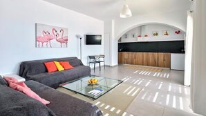 Een moderne woonkamer met een bank, een glazen salontafel en een schilderij van flamingo's.