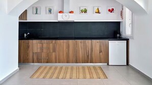 Een moderne keuken met houten kastjes, een zwart aanrecht en een witte koelkast.