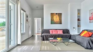 Een moderne woonkamer met een bank, een glazen salontafel en een schilderij aan de muur.