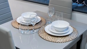 Mesa posta com pratos, copos e um jogo americano trançado.