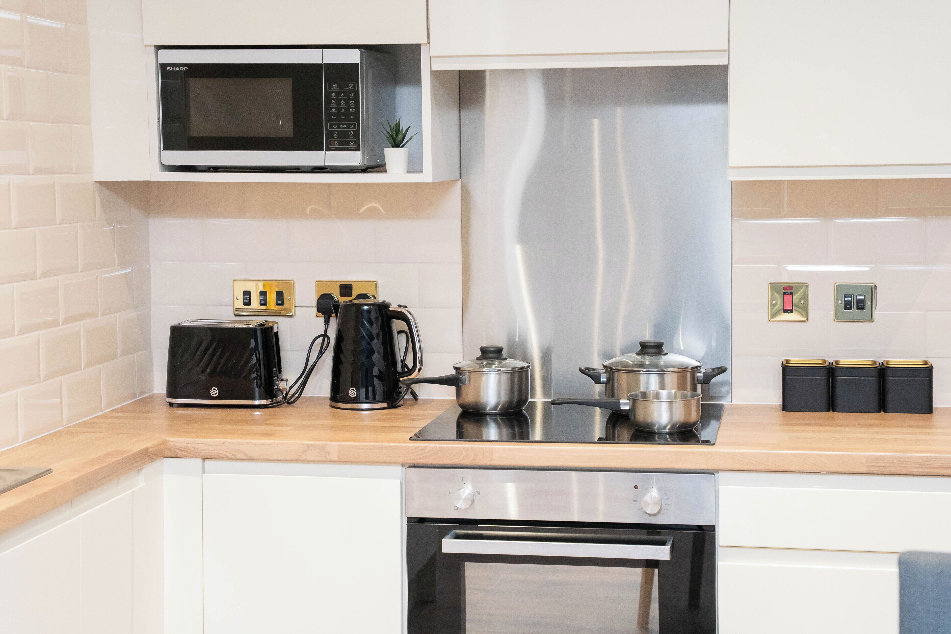 Una cocina moderna equipada con microondas, tostadora, hervidor, estufa, horno y armarios.