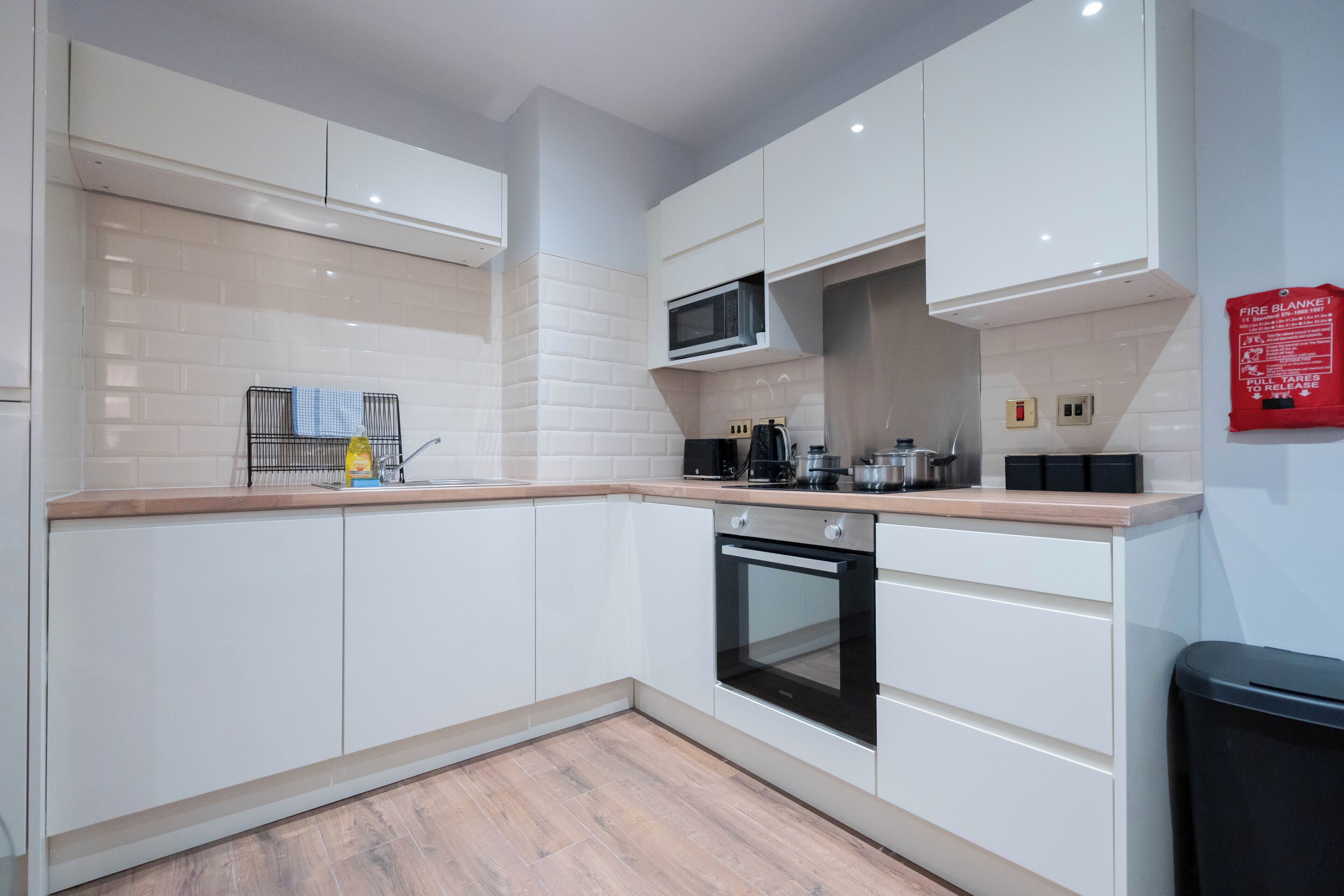 A modern kitchen with white cabinets, a microwave, an oven, and a coffee maker.