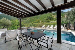 A covered outdoor area with a pool, white chairs, and a table. - Villa 'Daphne Pool and Jacuzzi' with Private Pool, Wi-Fi and Air Conditioning (Vescina)