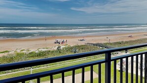A beach view from a balcony with a railing, ocean, and people on the sand. - Indies House 307 (Ormond Beach)