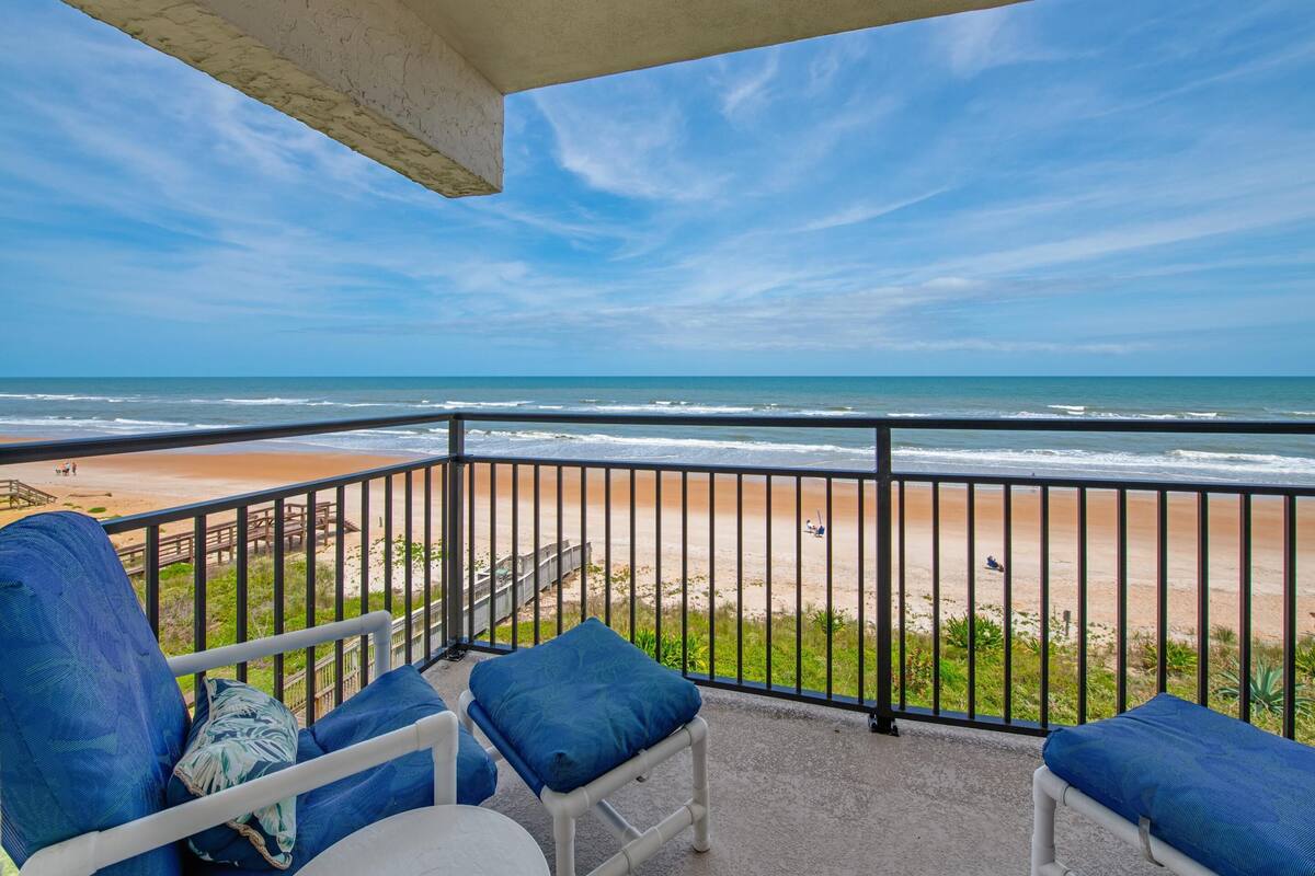 A balcony with a view of the beach and ocean.