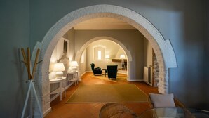 Ein gewölbter Korridor mit Kamin, Sitzgelegenheit und Lampe.