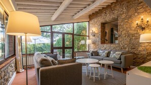 Ein gemütliches Wohnzimmer mit Steinwand, einer Couch, zwei kleinen Tischen und einer großen Stehlampe.