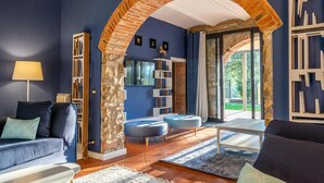 Un salon avec une arche en briques, un canapé, des poufs, une table basse et une bibliothèque.