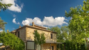 Une maison en pierre avec un patio, un jacuzzi et une pelouse.