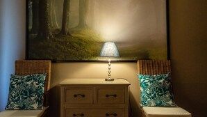 Ein Nachttisch mit Schubladen, eine Lampe und zwei Stühle mit gemusterten Kissen.