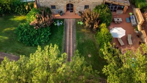 Ein Steinhaus mit Ziegeldach, einem Swimmingpool und einer Terrasse mit Gartenmöbeln.