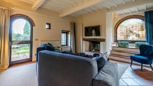 Ein Wohnzimmer mit einer Couch, einem Kamin, einem Fernseher und Blick ins Freie.