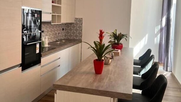 A modern kitchen with a central island, built-in appliances, and a dining area with chairs. - Residenza Colonna (Lanuvio)