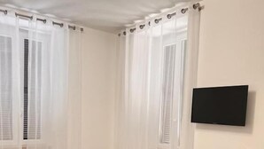 A bedroom with a bed, a desk, a chair, a TV, and a speaker. - Residenza Colonna (Lanuvio)