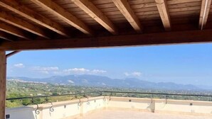 An open terrace with a view of distant mountains, a wooden ceiling, and a tiled floor. - Residenza Colonna (Lanuvio)