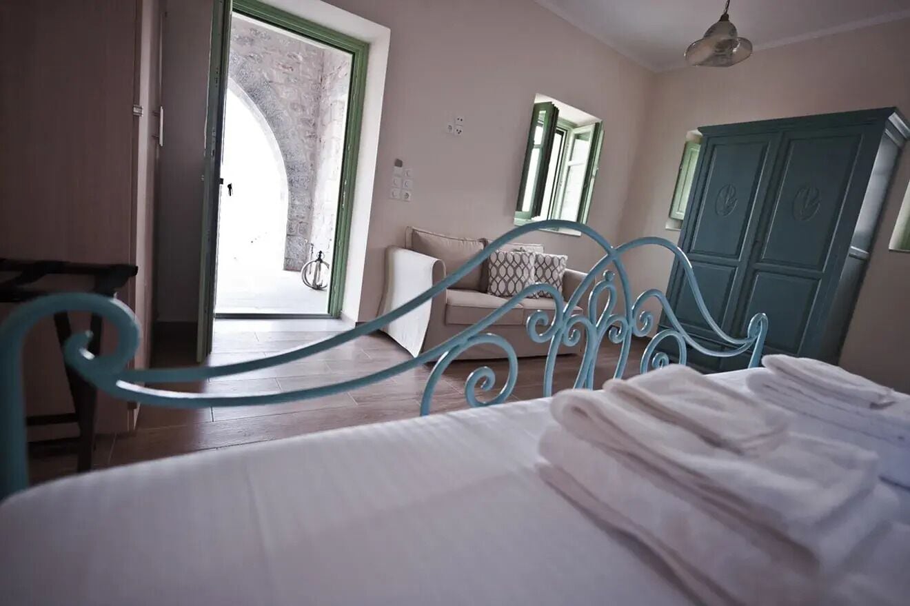 A bedroom with a bed, a door leading to an outdoor area, a mirror, and a wardrobe.