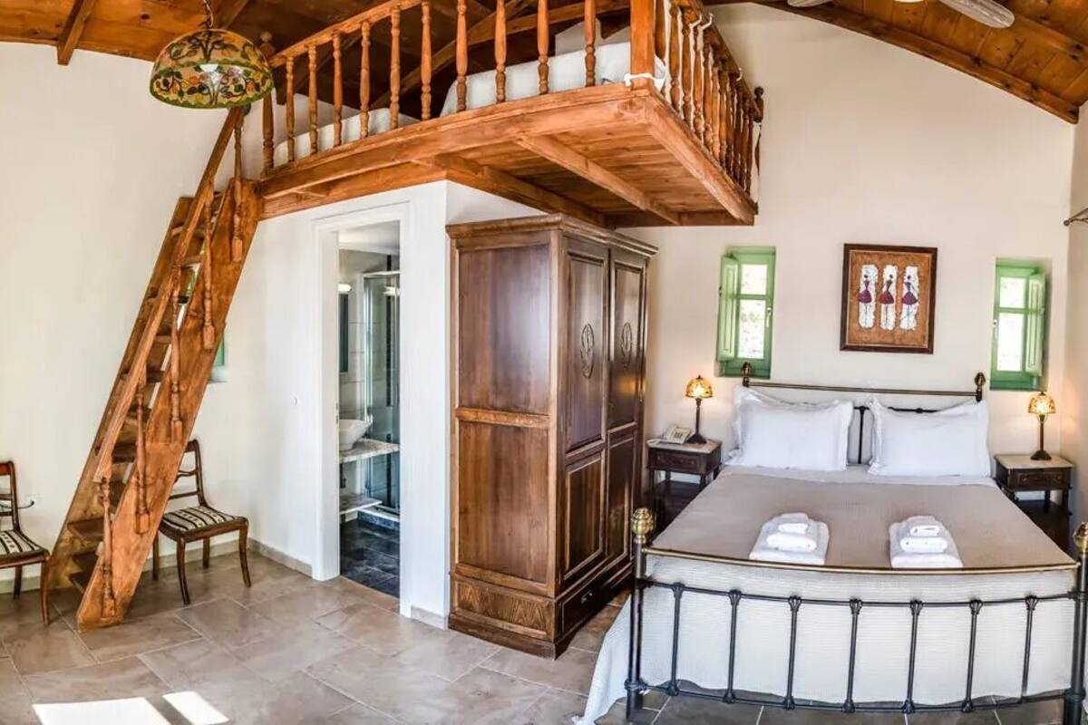 Ein Schlafzimmer mit einem großen Bett, einer Holztreppe und einem Kleiderschrank.