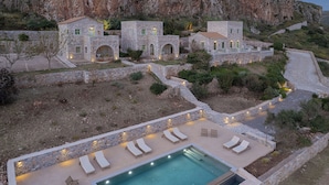 A stone villa with a swimming pool, lounge chairs, and a stone wall. - Alkyon Seaside Studios (East Mani)