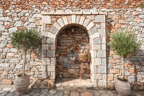 A stone archway with potted plants on either side. - Alkyon Seaside Studios (East Mani)
