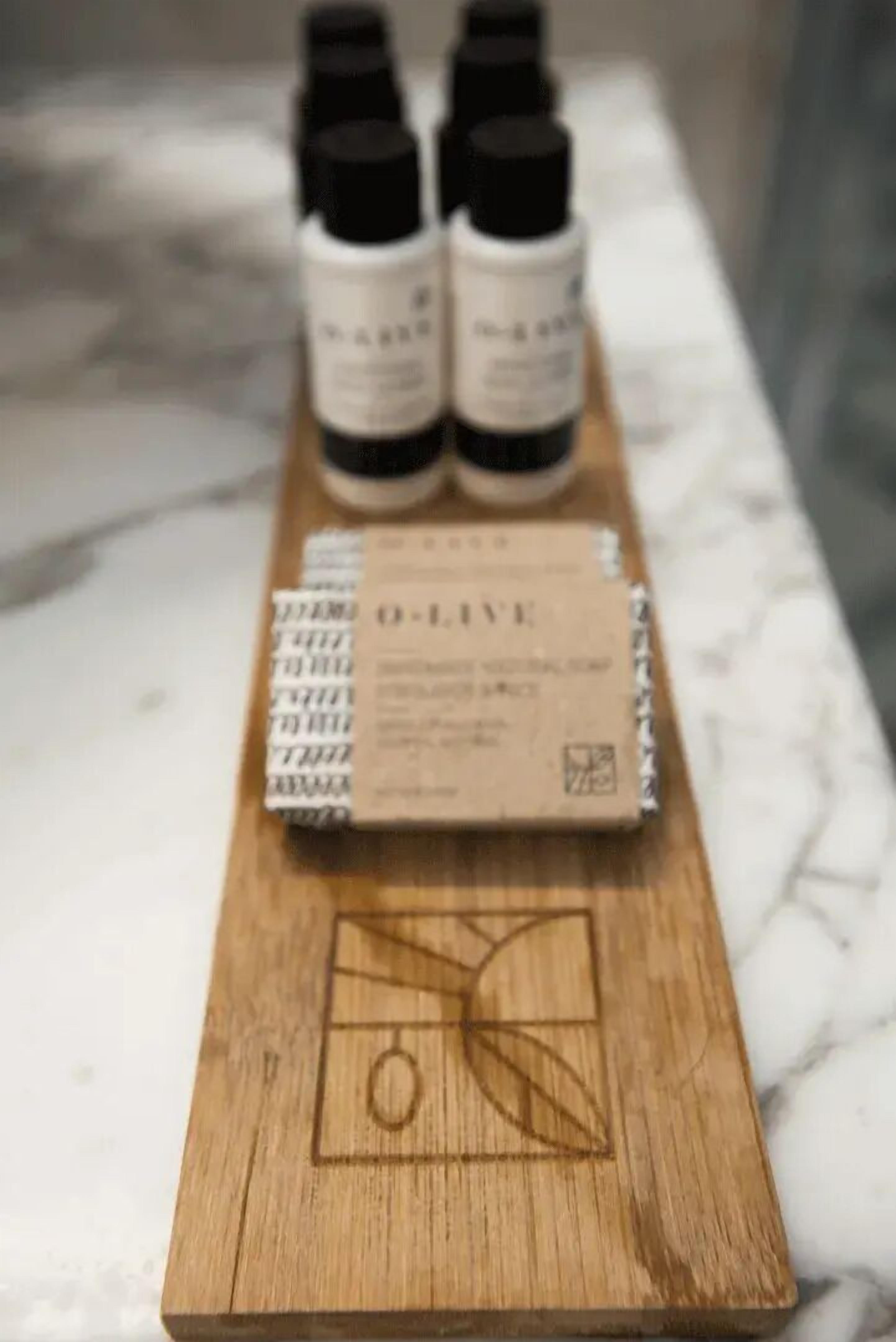 A wooden tray with a box labeled 'O-Live' and several small bottles on a marble surface.