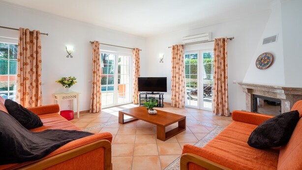 Een woonkamer met oranje banken, een televisie en een open haard.